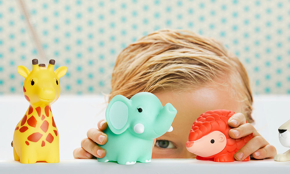 A young boy sits in the bath playing with Munchkin Wildlove Bath Squirts