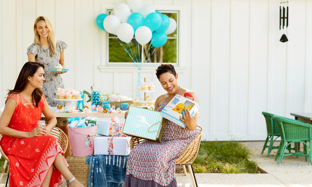 Women opening presents at a baby shower with friends.