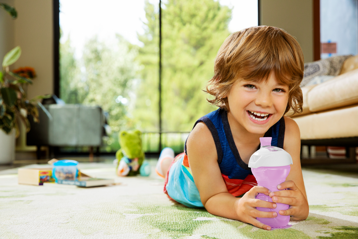 Close up of a purple Munchkin Divider Suction Plate on a highchair, and a toddler's hand picking up food with a spoon